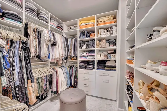 a view of walk in closet with clothes and shoes