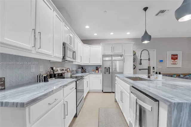 a kitchen with kitchen island granite countertop a sink counter space cabinets and stainless steel appliances
