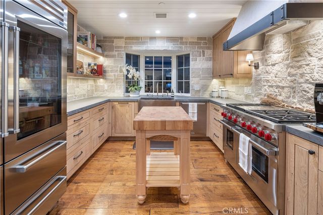 a large kitchen with stainless steel appliances granite countertop lots of counter top space and wooden floor