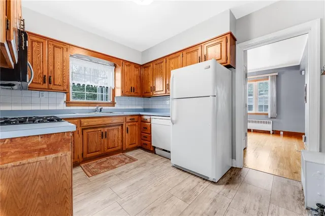 a kitchen with a refrigerator a stove top oven a sink and a window