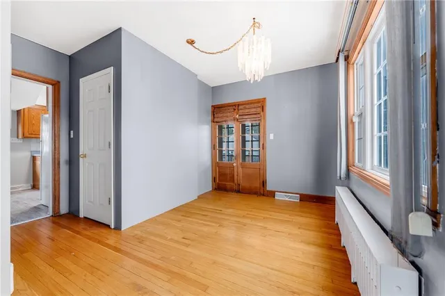 a view of an empty room with window and wooden floor