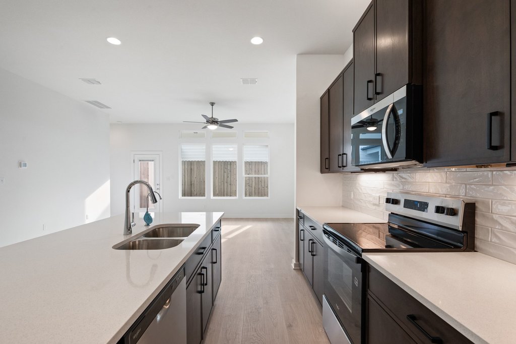 2205 Cento Walk Round Rock, TX 78664 - Photo 5 of 32 Kitchen featuring stainless steel appliances, light wood-type flooring, light stone counters, recessed lighting, and decorative backsplash
