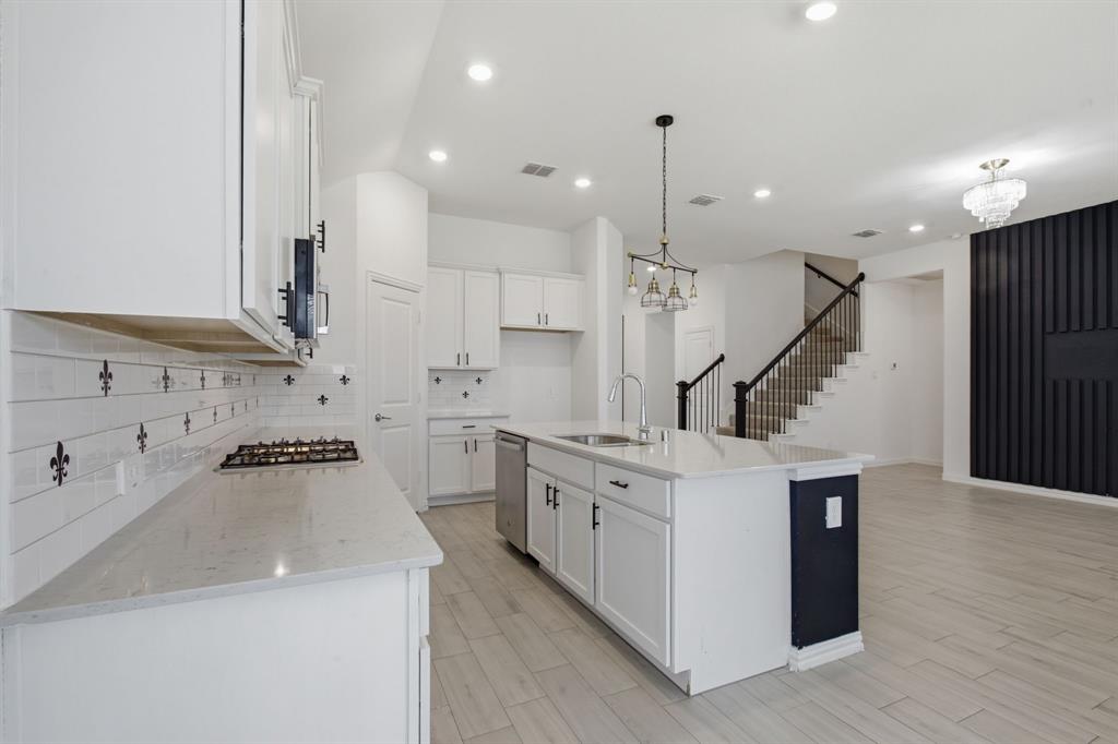 1710 Highwood Road Forney, TX 75126 - Photo 16 of 25 Bright kitchen featuring white cabinetry, light-toned countertops, a central island with a sink, and stainless steel appliances