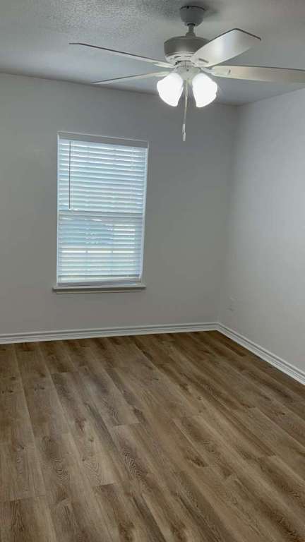 14205 Prairie Sod Lane Elgin, TX 78621 - Photo 21 of 24 a view of an empty room with chandelier fan and wooden floor