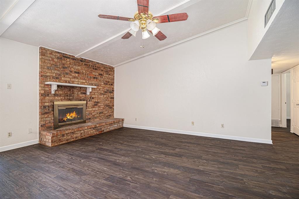 1814 Addington Drive Carrollton, TX 75007 - Photo 6 of 24 Unfurnished living room with ceiling fan, a textured ceiling, a fireplace, and dark hardwood / wood-style floors