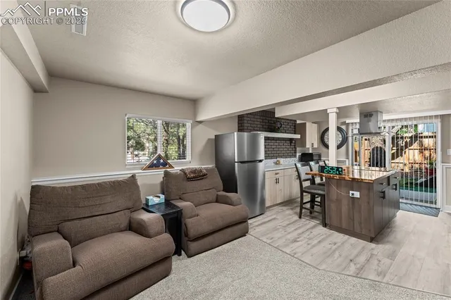 a living room with furniture and a refrigerator