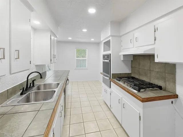 a kitchen with granite countertop a sink a stove and cabinets