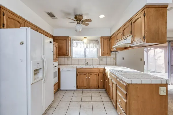 a kitchen with stainless steel appliances granite countertop a refrigerator a sink dishwasher and white cabinets with wooden floor