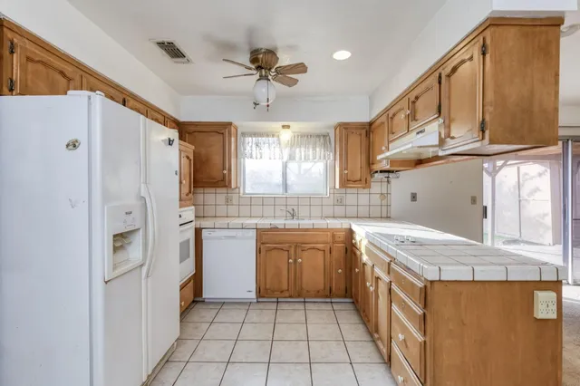 a kitchen with stainless steel appliances granite countertop a refrigerator a sink dishwasher and white cabinets with wooden floor