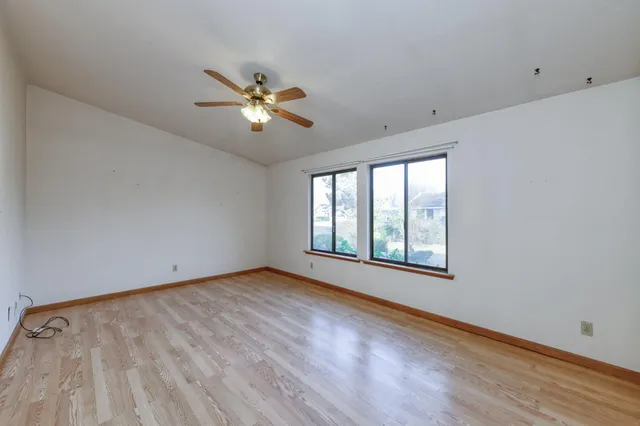 a view of empty room with wooden floor and fan