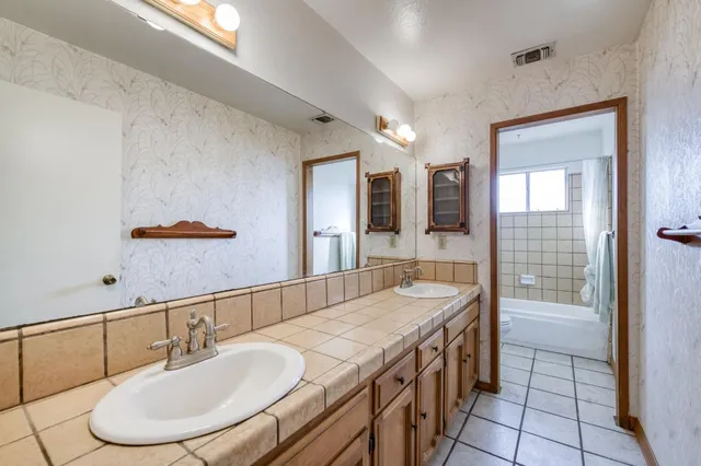 a bathroom with a granite countertop sink a mirror and a shower