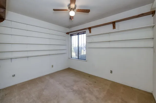 an empty room with a ceiling fan and window