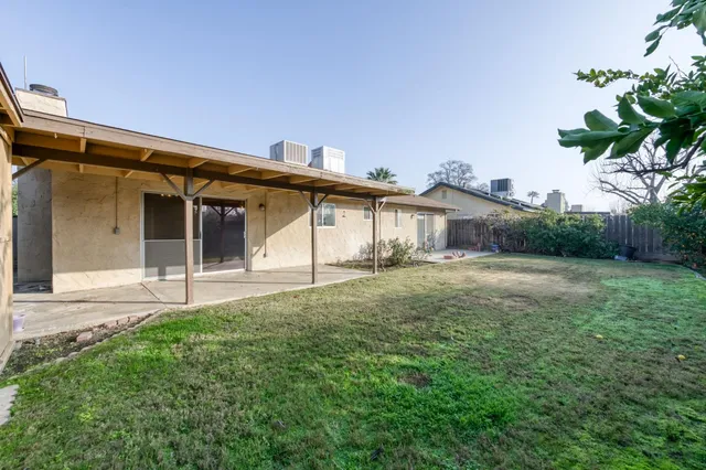 a white house with a small yard and large trees