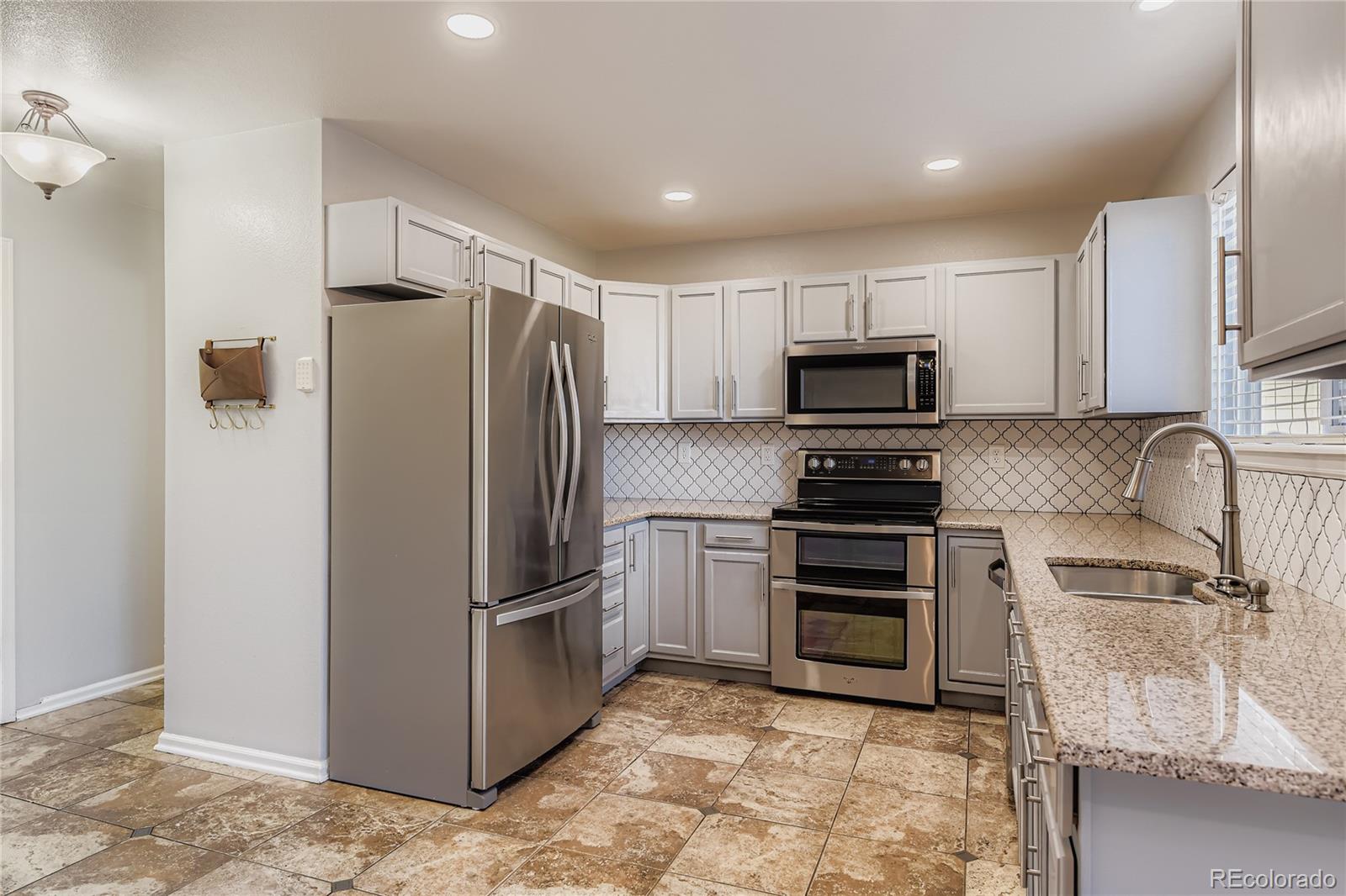 4927 Tarcoola Lane Highlands Ranch, CO 80130 - Photo 3 of 20 a kitchen with granite countertop a refrigerator and a sink