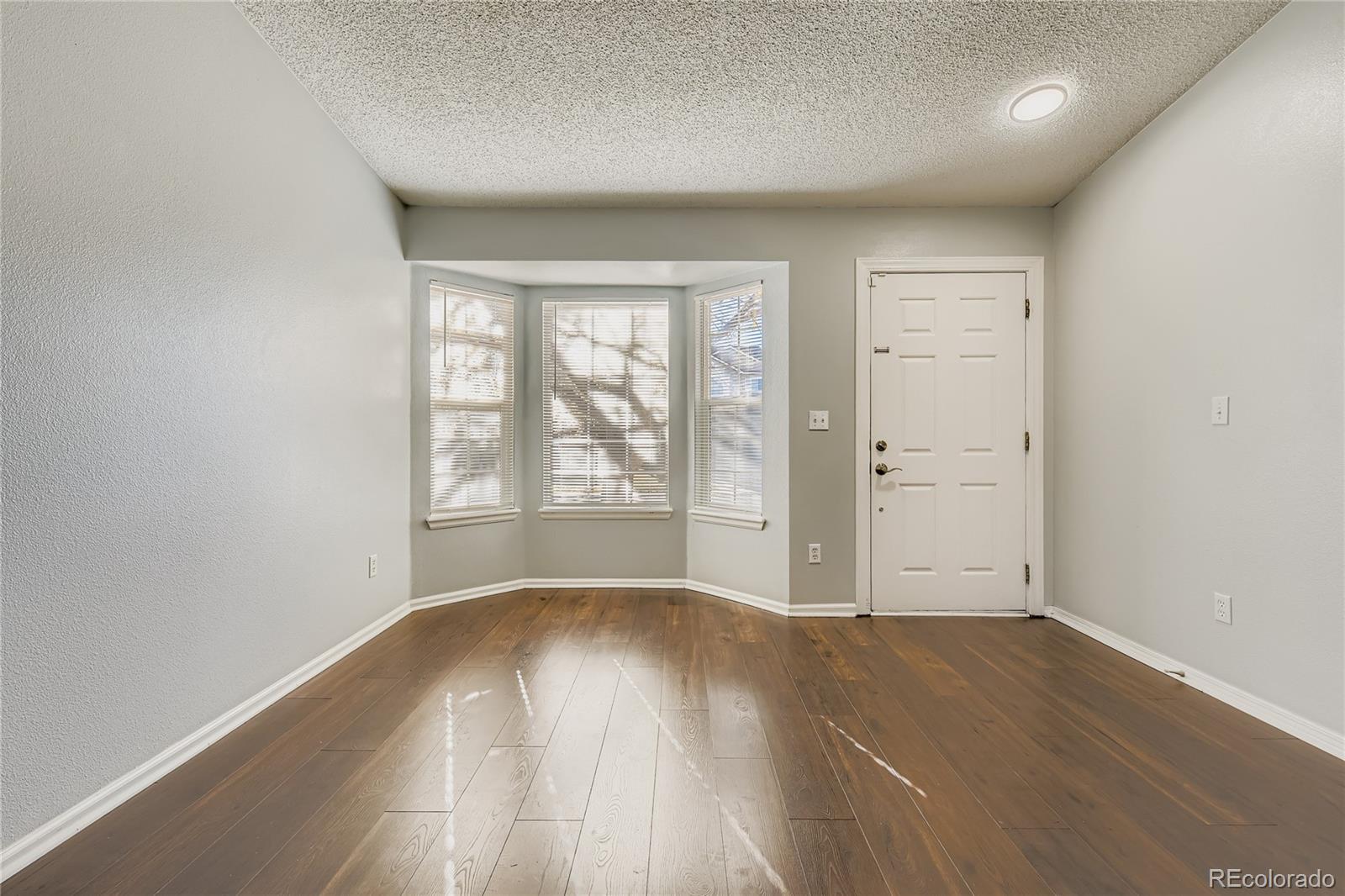 4927 Tarcoola Lane Highlands Ranch, CO 80130 - Photo 4 of 20 an empty room with wooden floor and windows