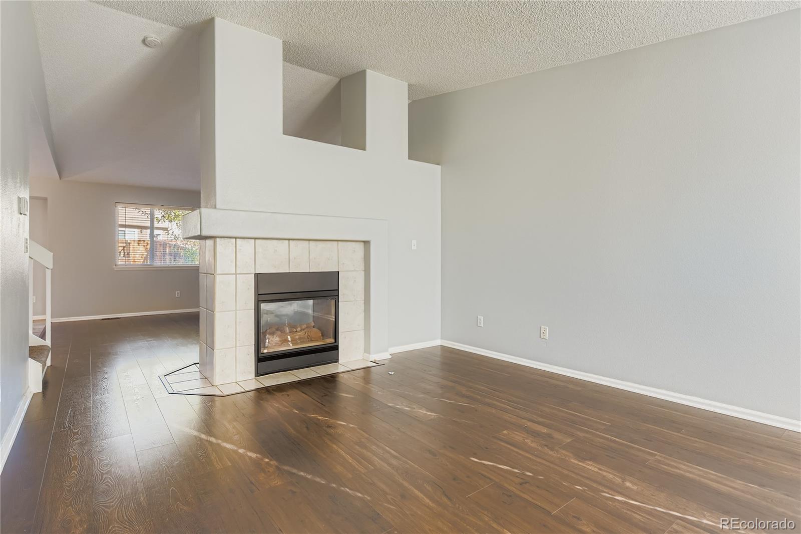 4927 Tarcoola Lane Highlands Ranch, CO 80130 - Photo 6 of 20 a view of an empty room with wooden floor fireplace and a window