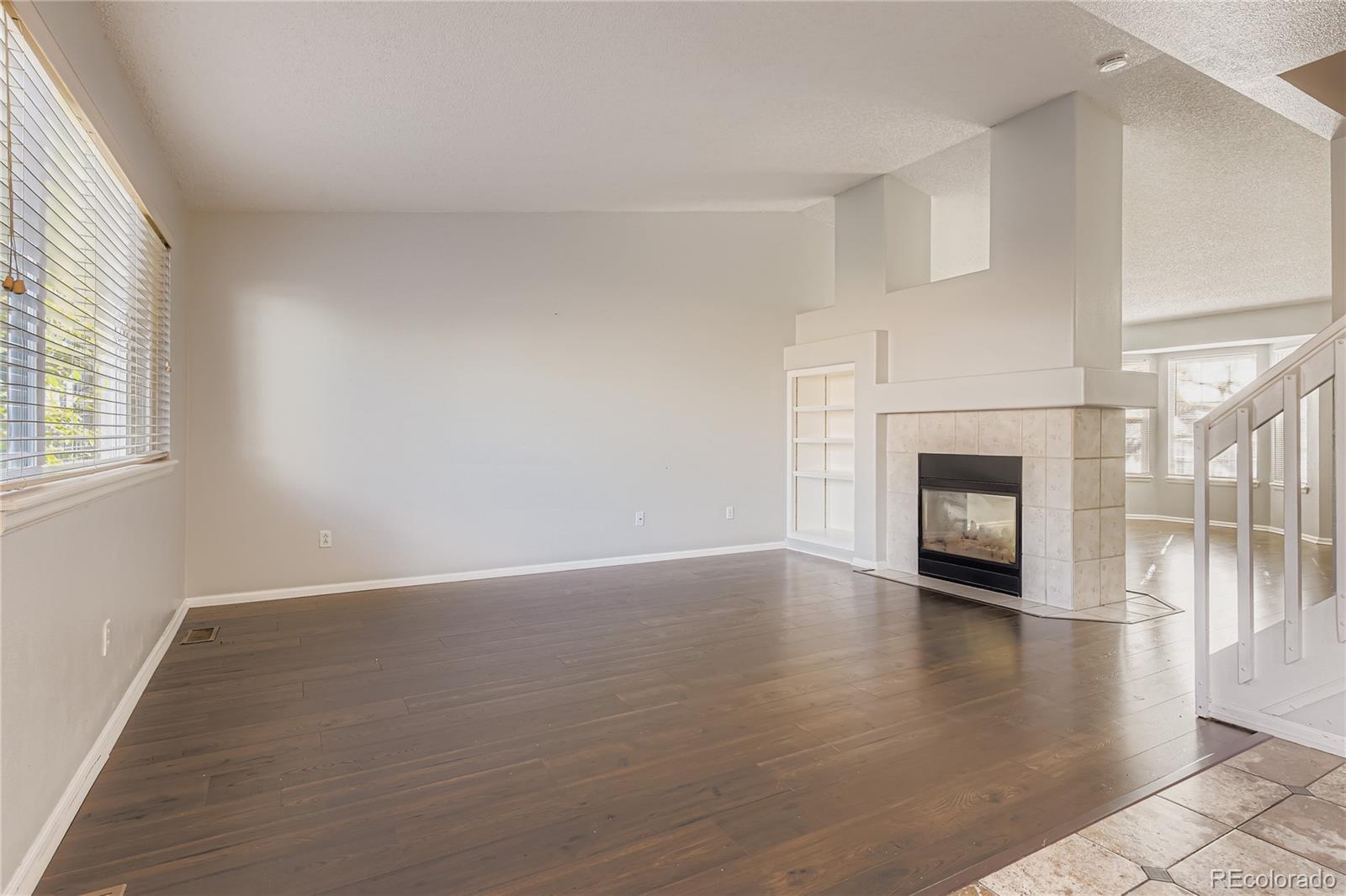 4927 Tarcoola Lane Highlands Ranch, CO 80130 - Photo 7 of 20 an empty room with wooden floor and fireplace