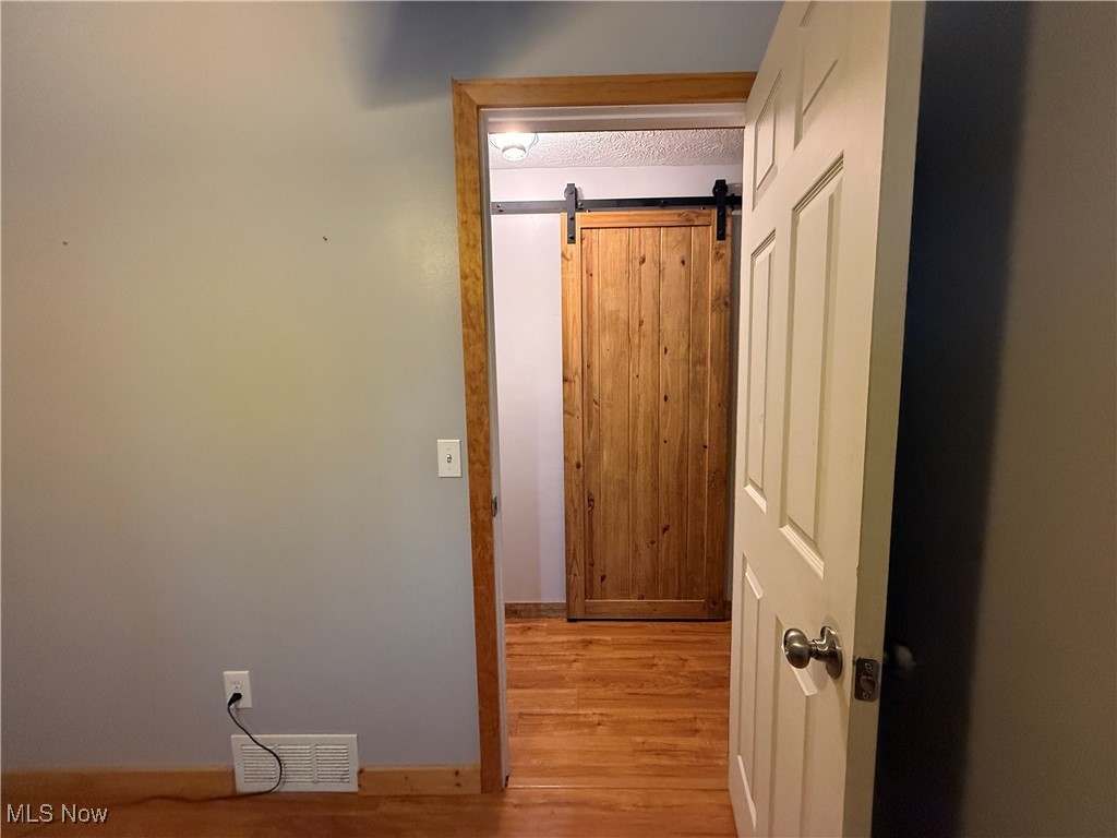 26017 Hartley Road Beloit, OH 44609 - Photo 16 of 28 Hall with a barn door and light hardwood / wood-style flooring