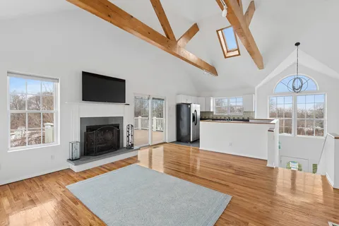 a living room with stainless steel appliances furniture a fireplace a flat screen tv and a window