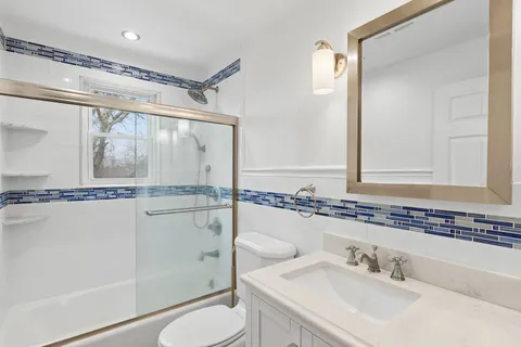 a bathroom with a sink a mirror a toilet and shower