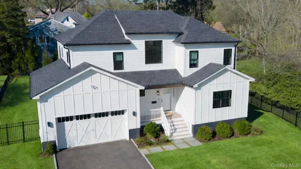 a view of a house with a yard plants and large tree