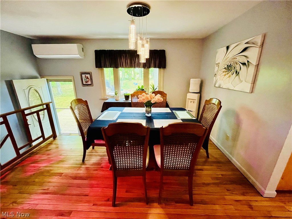 7220 Doty Road Madison, OH 44057 - Photo 30 of 50 Dining area featuring a notable chandelier, hardwood / wood-style floors, and a wall mounted air conditioner