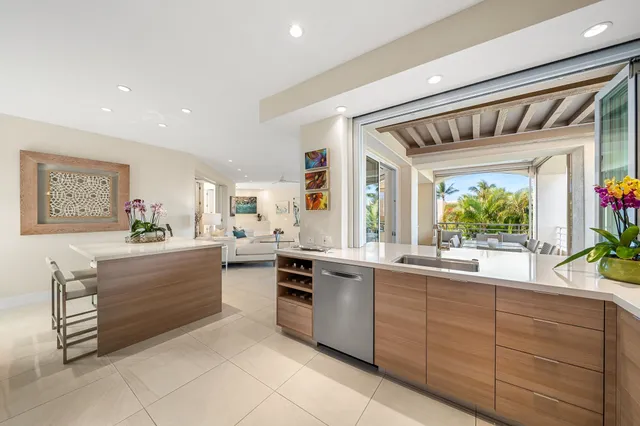 a kitchen with stainless steel appliances kitchen island granite countertop a dining table chairs and white cabinets