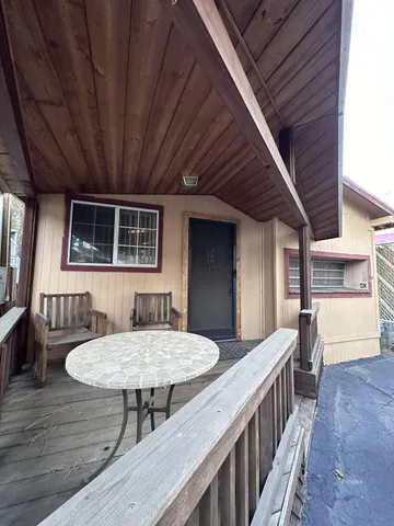 a view of a patio with table and chairs with wooden floor and fence