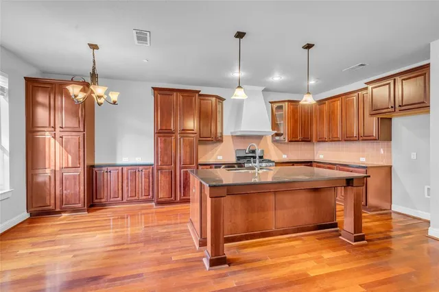 a kitchen with stainless steel appliances granite countertop a refrigerator a stove a sink dishwasher and a oven with wooden floor