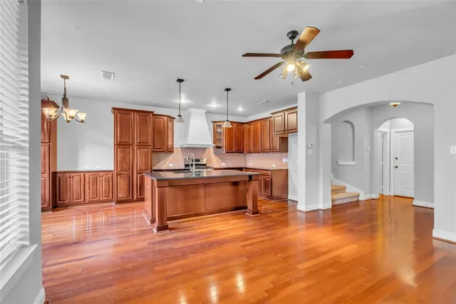 a open kitchen with granite countertop a stove a sink dishwasher a refrigerator and a dining table with wooden floor