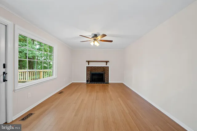 a view of an empty room with a window and fireplace