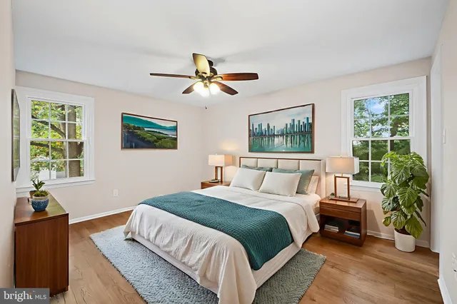 a spacious bedroom with a large bed a chandelier and windows