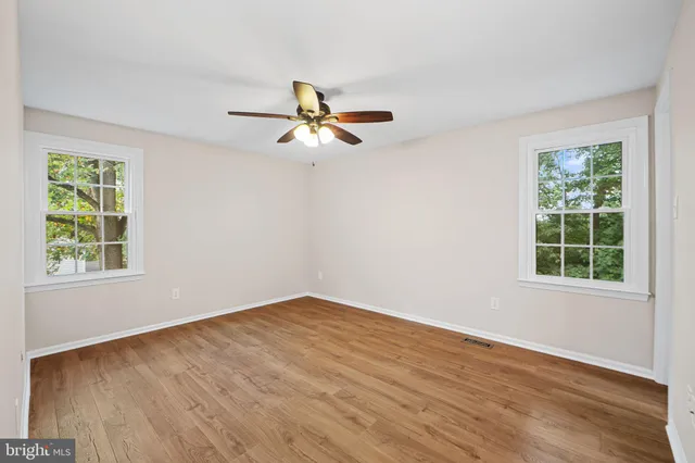 a view of empty room with wooden floor and fan