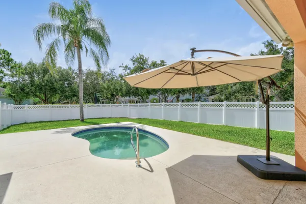a small pool with a table and chairs under an umbrella