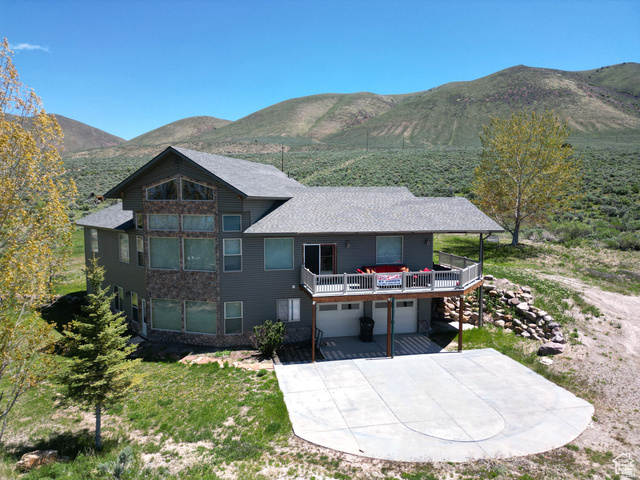 1940 East Shore Road St. Charles, ID 83272 - Photo 1 of 64 Rear view of property with an attached garage, a patio area, a deck with mountain view, driveway, and roof with shingles