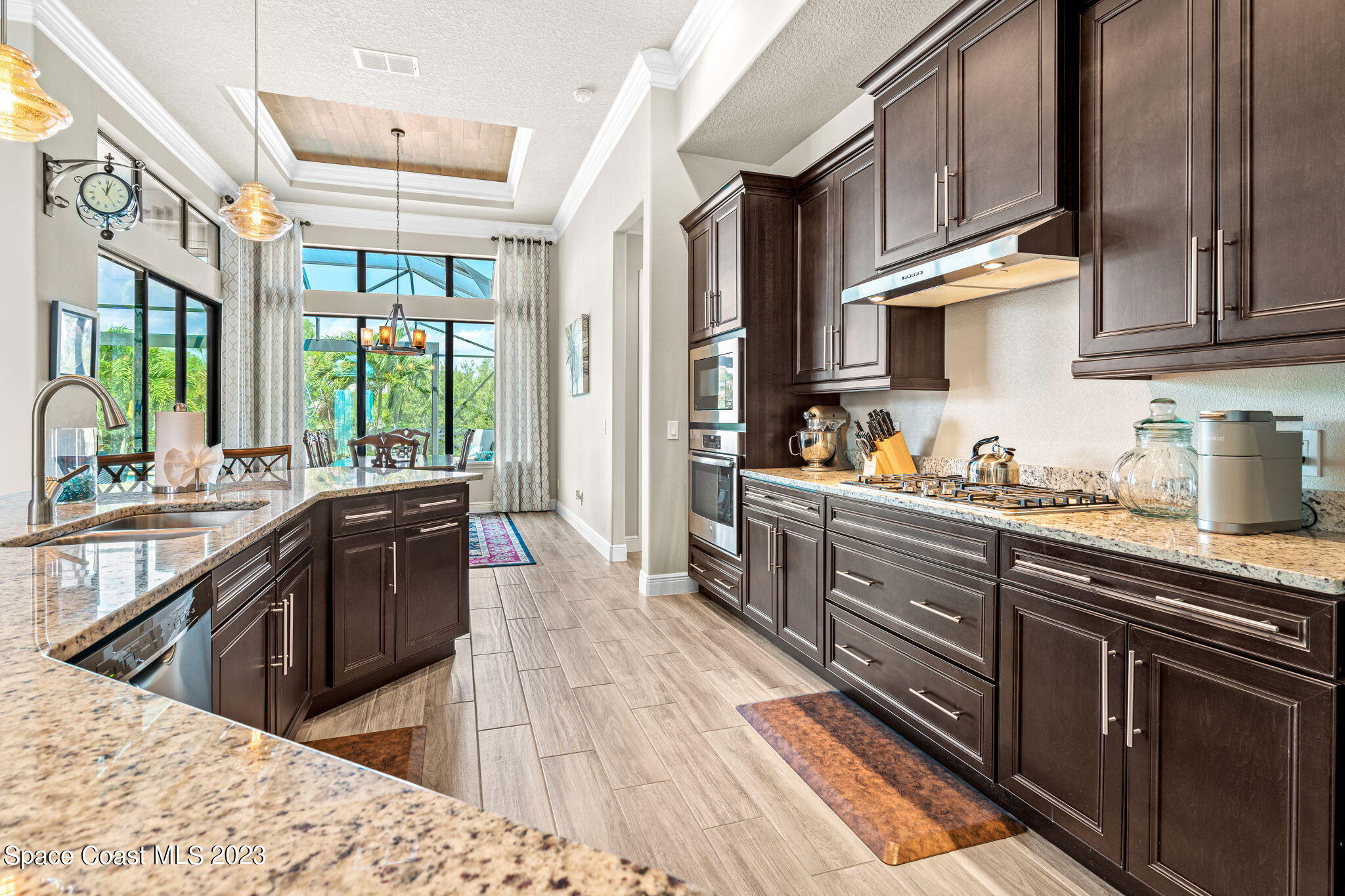 5530 Calder Drive Melbourne, FL 32940 - Photo 19 of 63 a kitchen with stainless steel appliances kitchen island granite countertop a stove a sink dishwasher and cabinets with wooden floor