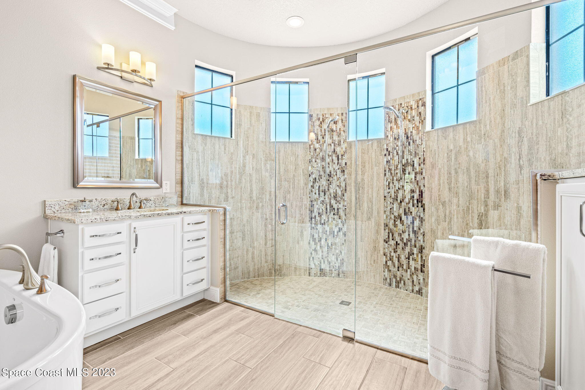 5530 Calder Drive Melbourne, FL 32940 - Photo 30 of 63 a bathroom with a double vanity sink a mirror a shower and a bathtub