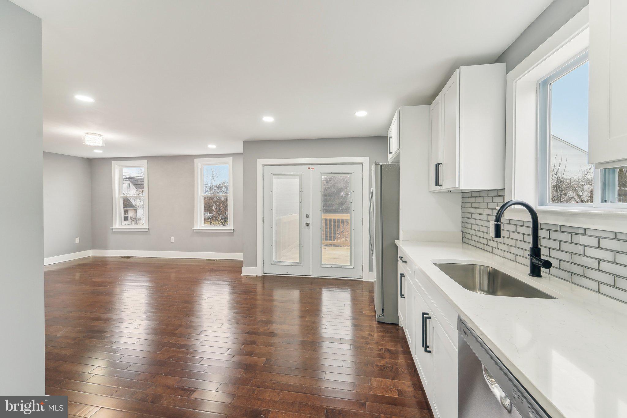 7008 Windsor Mill Road Baltimore, MD 21207 - Photo 15 of 34 a large white kitchen with wooden floor a sink and stainless steel appliances