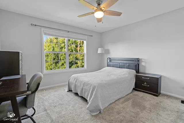 a bedroom with a bed computer on desk and a chair