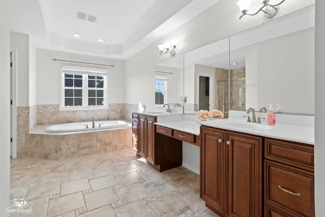 a spacious bathroom with a tub sink shower and mirror