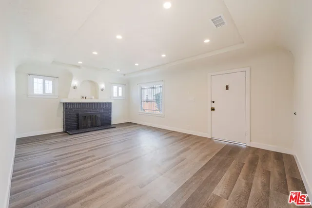 an empty room with wooden floor and fireplace