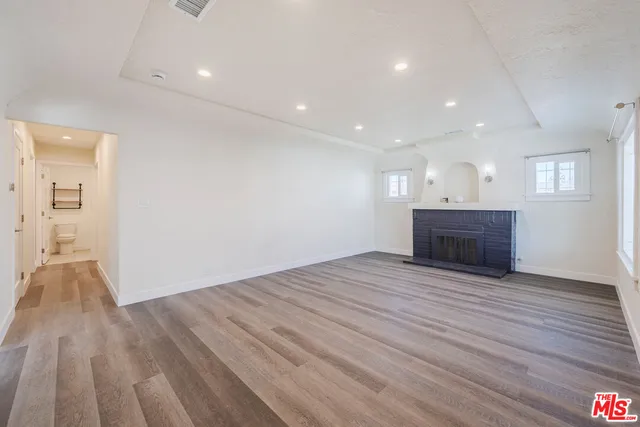 a view of empty room with wooden floor and fireplace