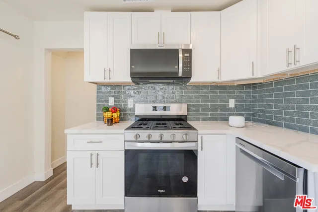 a kitchen with white cabinets and appliances