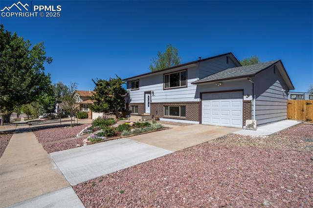 3870 Half Turn Road Colorado Springs, CO 80917 - Photo 2 of 34 View of front of home featuring brick siding, driveway, an attached garage, and fence