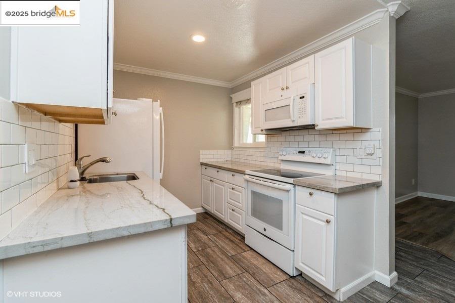 1505 Kirker Pass Road, Unit 170 Concord, CA 94521 - Photo 8 of 18 Kitchen featuring tasteful backsplash, light stone counters, white appliances, wood finish floors, and white cabinetry