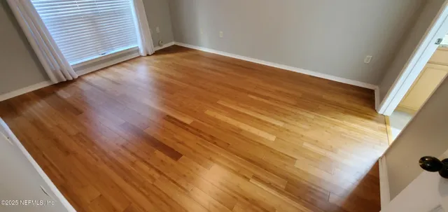 a view of an empty room with wooden floor and a window
