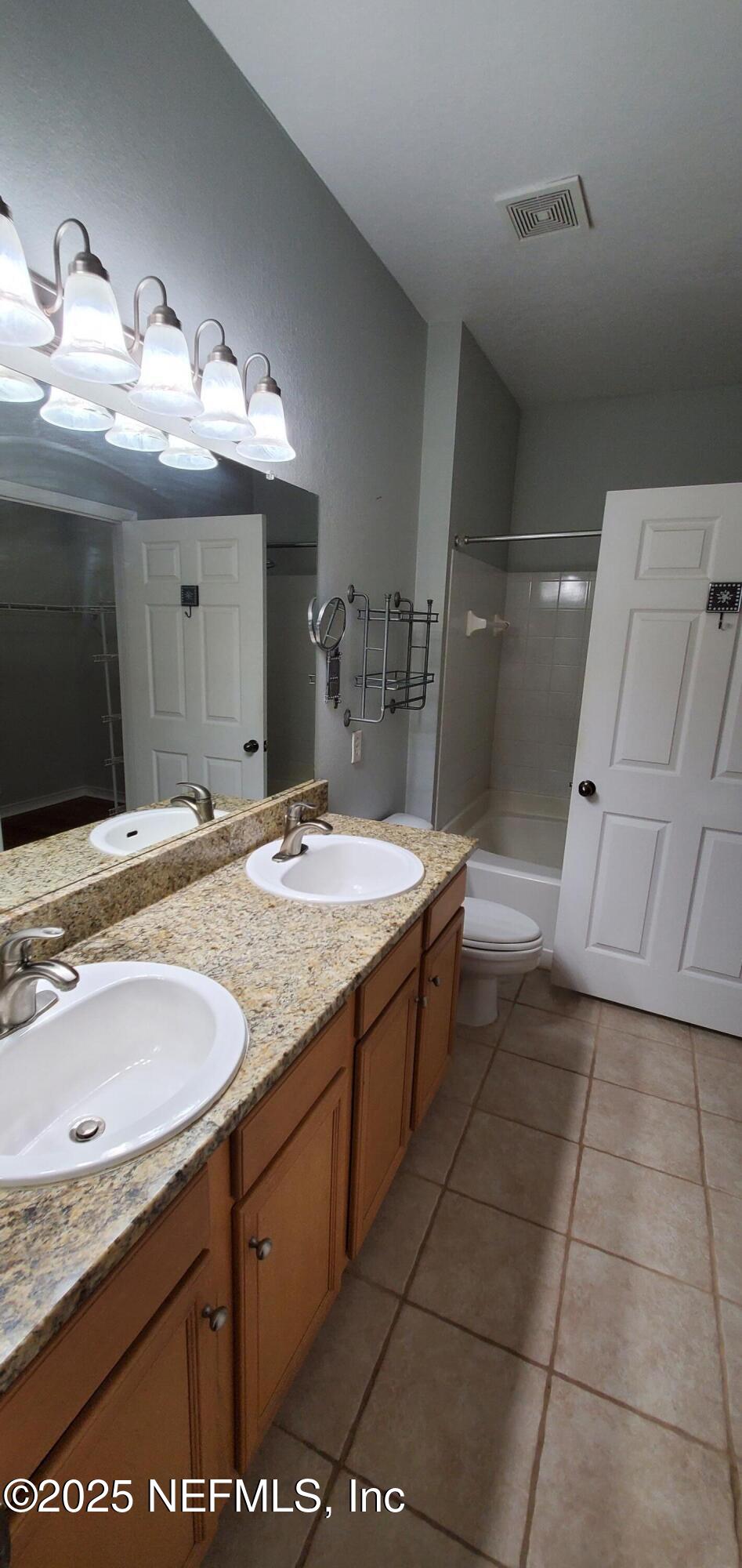 7800 Point Meadows Drive, Unit 1012 Jacksonville, FL 32256 - Photo 26 of 38 a bathroom with a granite countertop sink a toilet and a mirror