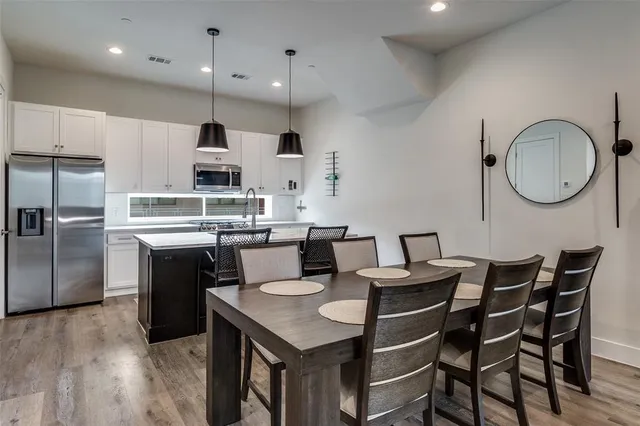 a kitchen with stainless steel appliances kitchen island granite countertop a table chairs and a refrigerator