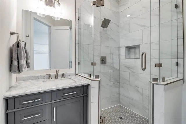 a bathroom with a granite countertop shower sink vanity and mirror