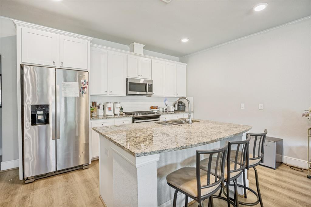 3545 Rashti Court Fort Worth, TX 76109 - Photo 10 of 36 a kitchen with stainless steel appliances granite countertop a kitchen island hardwood floor and a refrigerator